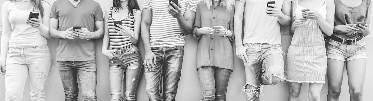 Grupo de amigos adolescentes mirando teléfonos móviles inteligentes